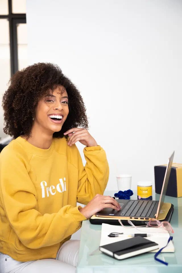 Woman on a computer smiling and showing white teeth