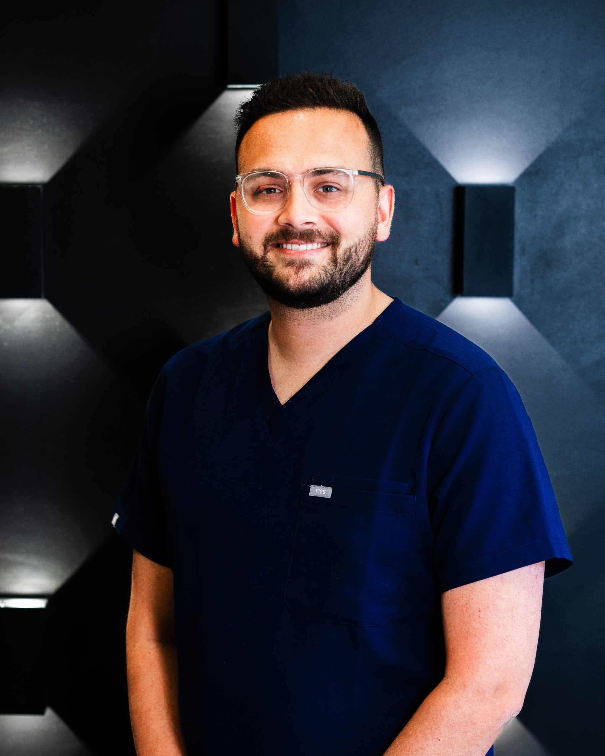 Dentist Dr Josh Patel smiling in blue scrubs