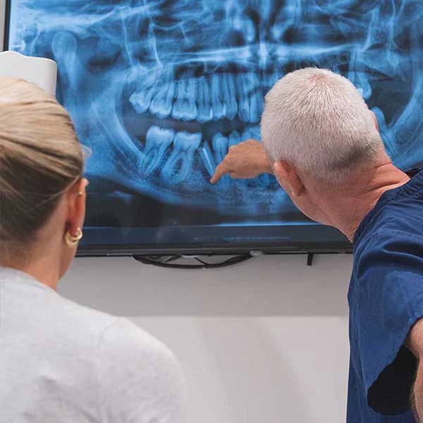 Two people examining a dental X ray on a screen.