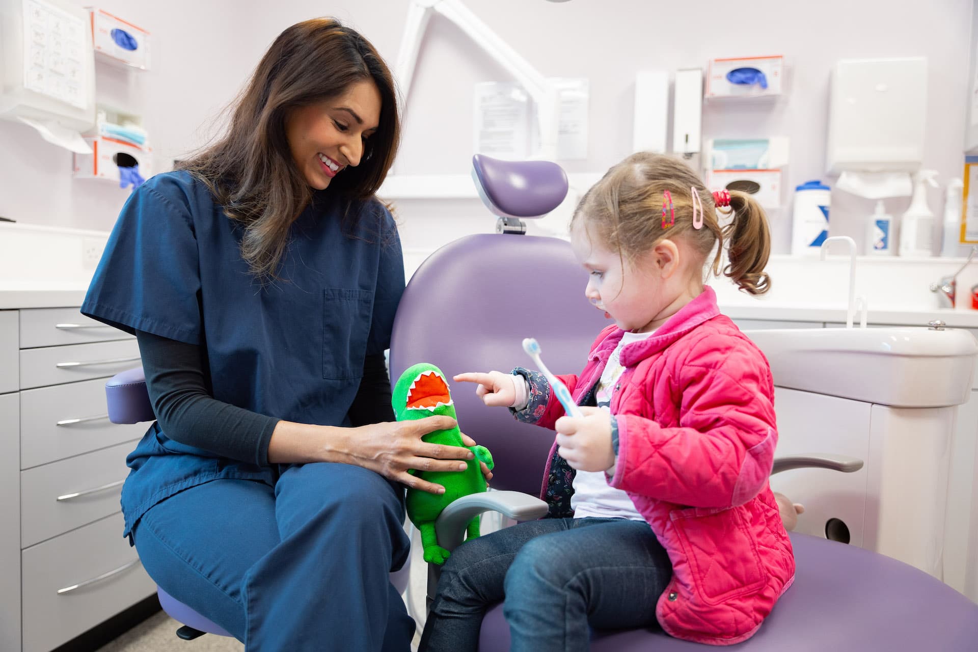 Girl being taught how to brush teeth